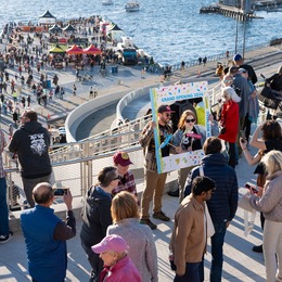Photo over the Overlook Walk with the water in the background with a crowd of people walking and posing for photos