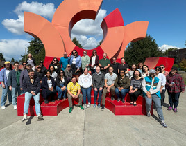 Group photo of OED staff in front of a red and orange art sculpture