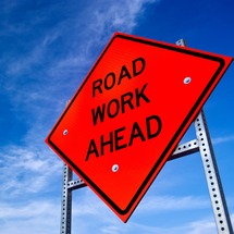 Road Work Ahead sign in front of a blue sky