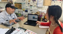 An older Asian man and young Asian woman talking in front of a laptop
