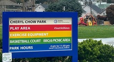A City of Seattle Park sign that reads "Cheryl Chow Park" with playground equipment in the background
