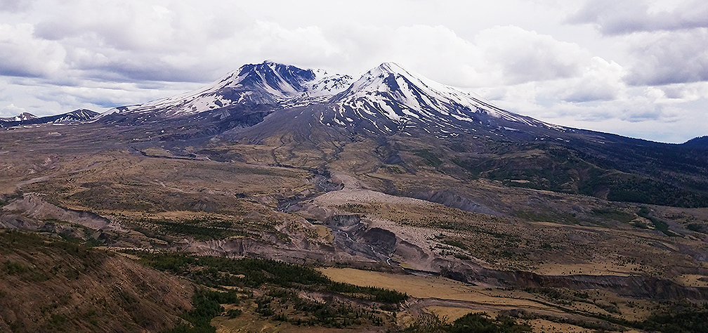 photograph of Mount St. Helens with limited snow cap and on a cloudy day