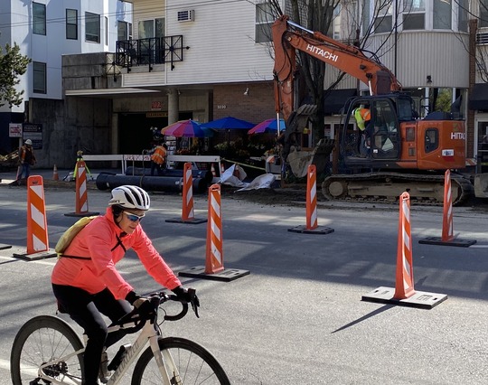 Person on a bike traveling past the water main construction on Eastlake Ave E