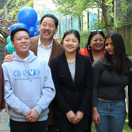 Three youth stand, smiling with Mayor Bruce Harrell