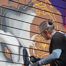 Man using spray paint can to create a mural