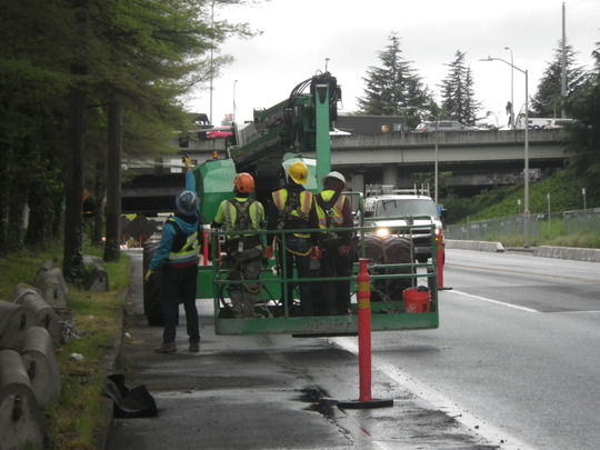 Crews use the eastbound bike lane on S Dearborn St to place equipment that lifts workers to the Dr. José Rizal Bridge for scaffolding work.
