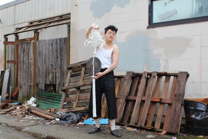 A man holds a large white knot with a steel coin in an alley.