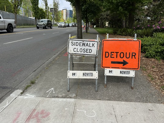 Image showing sidewalk next to traffic lanes on Denny Way with signs reading "Sidewalk Closed" and "Detour"