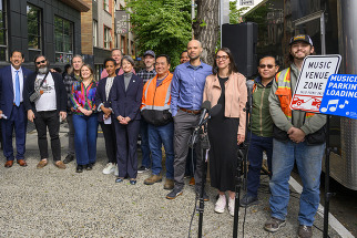 group of city officials and the mayor stand in a group with the new music venue load zone signs