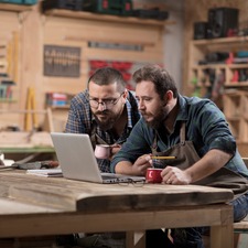 two men in a workshop looking at a laptop