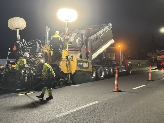 Image of construction crews with paving truck doing roadwork at night