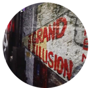 Painted sign on a cement wall that says "The Grand Illusion CInema"