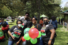 Gathering of people dressed in black shirts, each holding colorful balloons, sharing a joyful moment at City of Seattle Juneteenth event