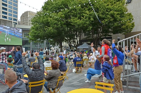 People attending a soccer watch party and cheering in the park