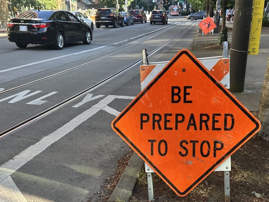 Image of city street and roadwork sign saying "be prepared to stop"