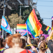 Crowd of people hold LGBTQIA+ Flags at a pride event