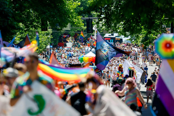 Thousands marching in Seattle's Pride Parade with several people holding rainbow flags and balloons