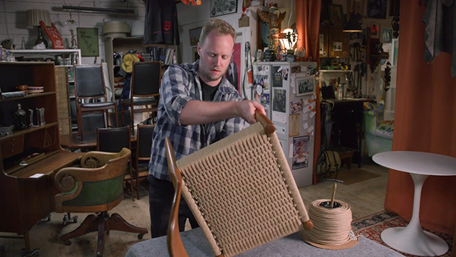 A person works on a chair using the Danish cord weaving technique
