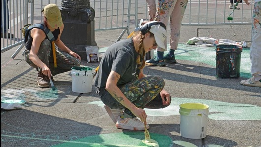 Artists painting art on a sidewalk