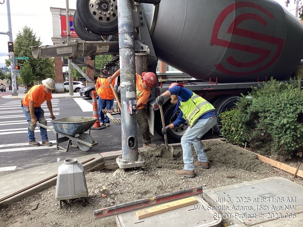 Crews pour sidewalk on the northwest corner of 15th Ave NW and NW Market St. Image taken July 3, 2025.