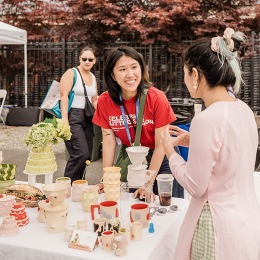 a vendor talking to a customer at an outdoor booth at celebrate saigon