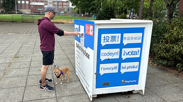 A voter turns in his ballot while walking his dog.