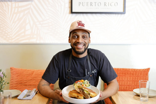 Chef and owner Jhonny Reyes displays off a plate of food at his Belltown restaurant, Lenox