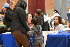 A woman and child talking to people at an event table about various resources and services