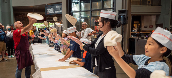 A person teaching kids how to toss pizza dough