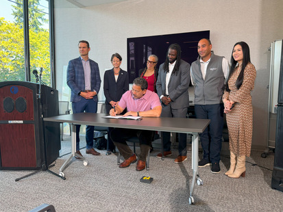 mayor signing bill with a group of people standing behind him