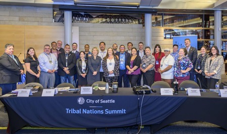 tribal nations summit and city of seattle leadership standing in front of a table for a group photograph
