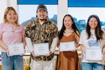 Four business owners standing in a line each showing a piece of paper