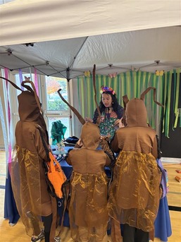  OPA staff member, Serenna Duncan, dressed up as a butterfly, talking about OPA’s work with three kids dressed as cockroaches for Harvest Fest. 