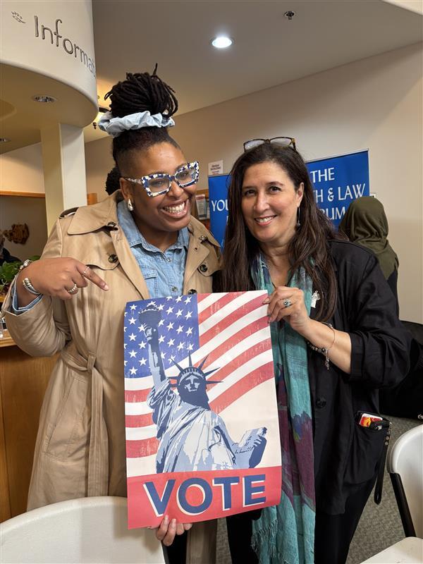 OPA staff holding a "Vote" poster that features the Statue of Liberty and the American Flag.