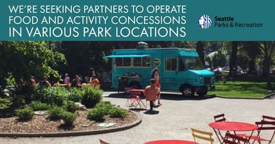 a blue food truck parked in a Seattle park with tables and chairs surrounding it