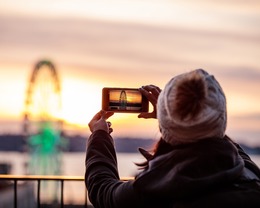 a person wearing a beanie taking a photo of the Ferris wheel 
