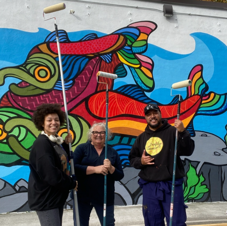 Three people standing in front of a newly painted mural
