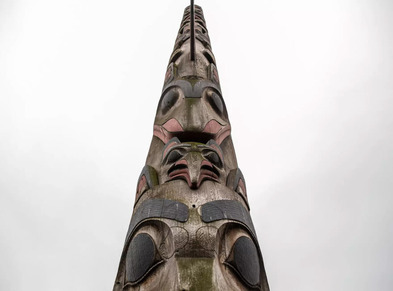 Image looking up at a totem pole against a cloudy sky
