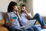 Couple sitting at home, using a laptop and a credit card for online shopping.