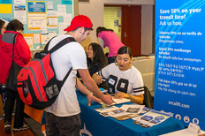 Photo of the Orca lyft Program booth at the Resource Fair. People talking about resources.