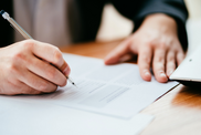 Close up photo of hands signing a form on a table