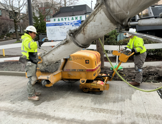 Crews pour new concrete for the curbs near E Lynn St.