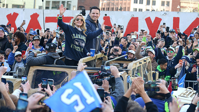 Seahawks head coach Mike Macdonald and wife Stephanie Macdonald wave to a sea of supporters.