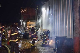 Firefighters working to access a commercial building on fire.