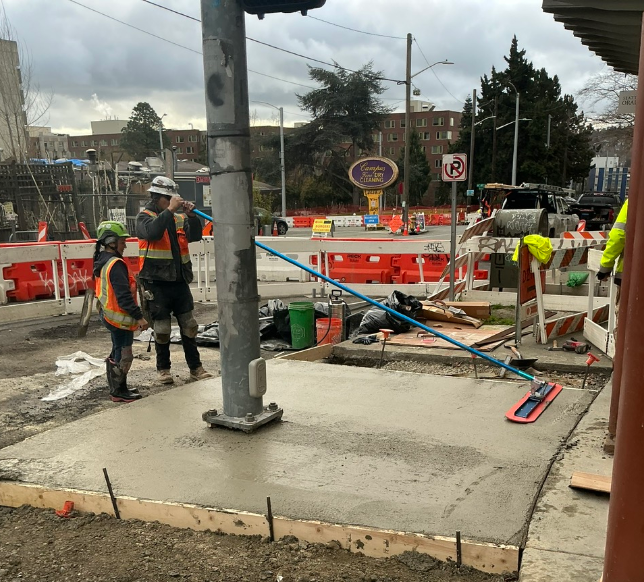 Crews smooth out new concrete on Roosevelt Way NE. 