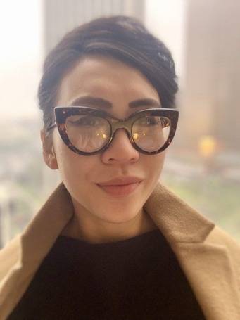 Amy is Vietnamese and wears heavy glasses and a stylish coat.
