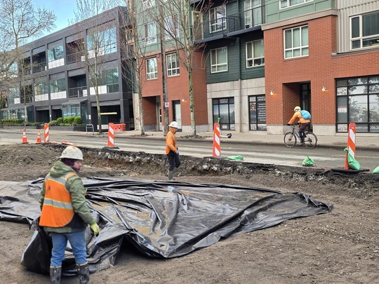 Crews covering excavated surfaces along Eastlake Ave E during poor weather. 