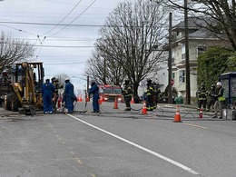 Firefighters providing fire suppression support while utility workers secure a severed natural gas line