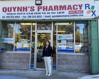 Mary Bui, owner of Quynh’s Pharmacy, stands in front of the repaired glass door
