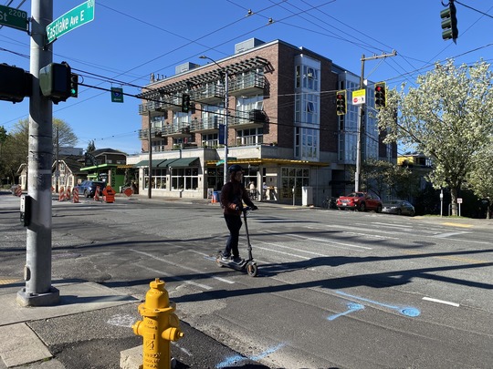 A person on a scooter traveling through the intersection of Eastlake Ave E and E Lynn St. 